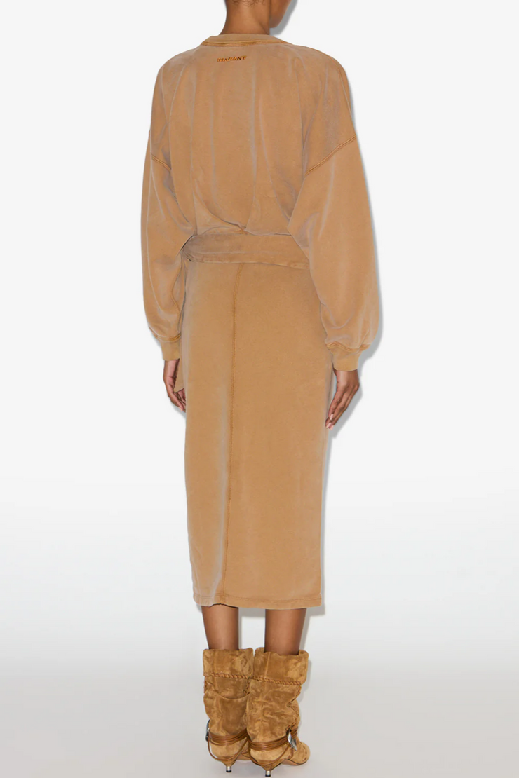 Person wearing a caramel dress with long sleeves on a white background