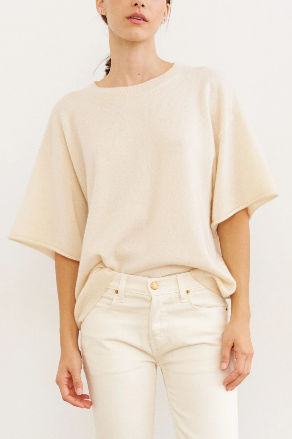 Person wearing a beige top and white pants on a plain background