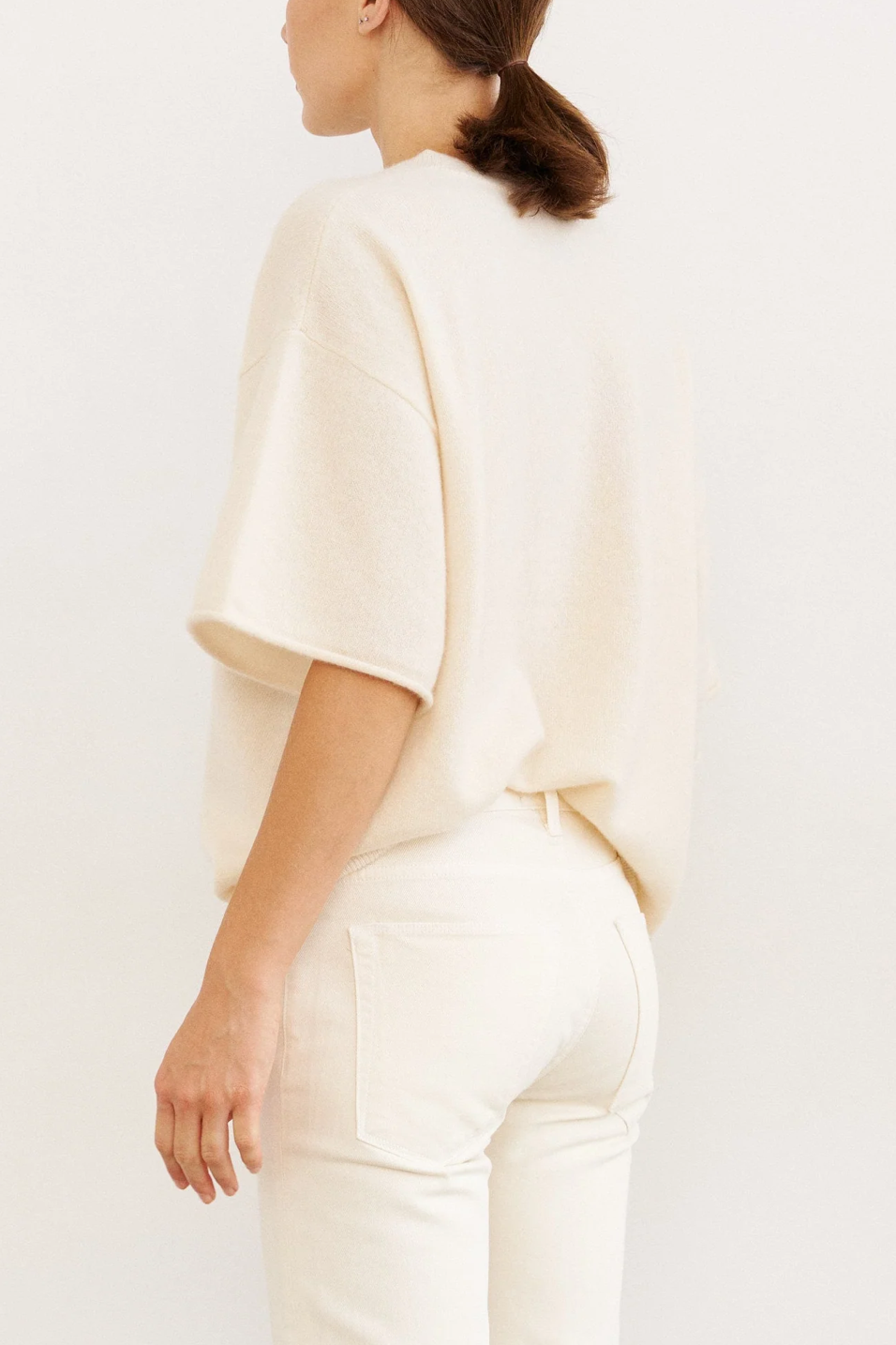 Person wearing a light-colored outfit on a plain background