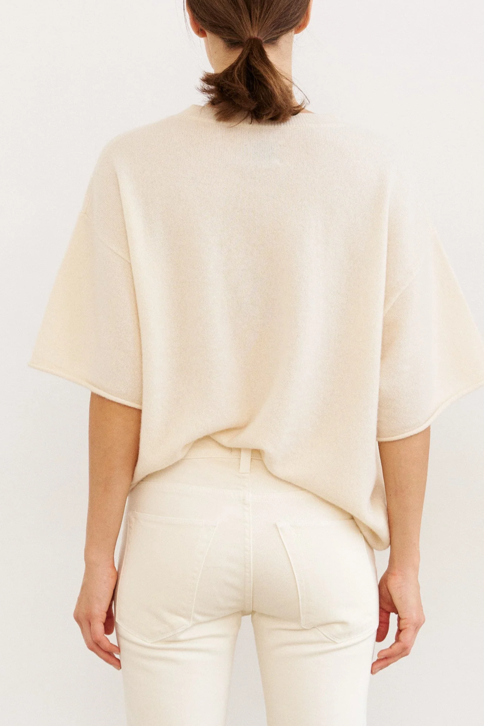 Person wearing a light beige top and pants on a white background