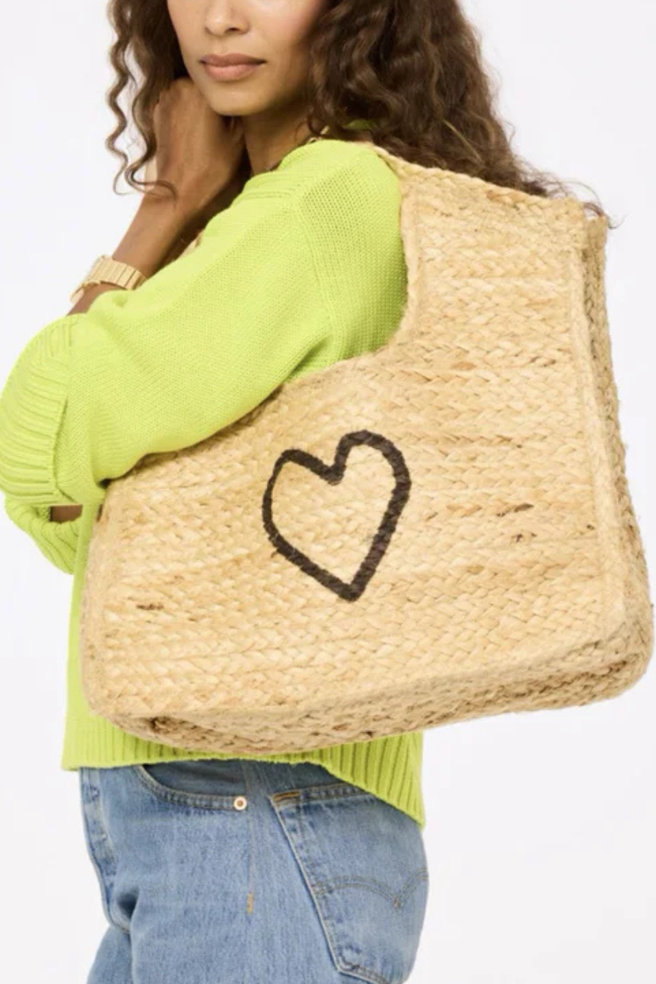 woman holding a woven bag with a heart design on a white background