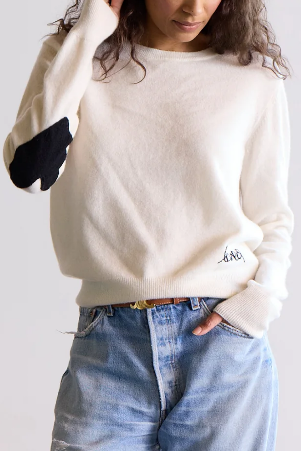Person wearing a cashmere sweater and blue jeans on a plain background