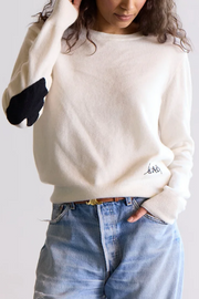 Person wearing a cashmere sweater and blue jeans on a plain background