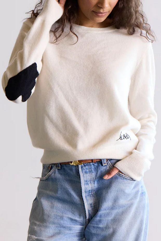 Person wearing a cashmere sweater and blue jeans on a plain background