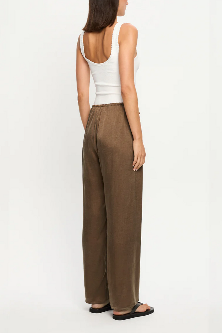 Woman wearing a white tank top and mocha wide-leg pants on a white background