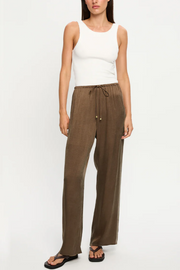 Woman wearing mocha pants and a white top on a white background