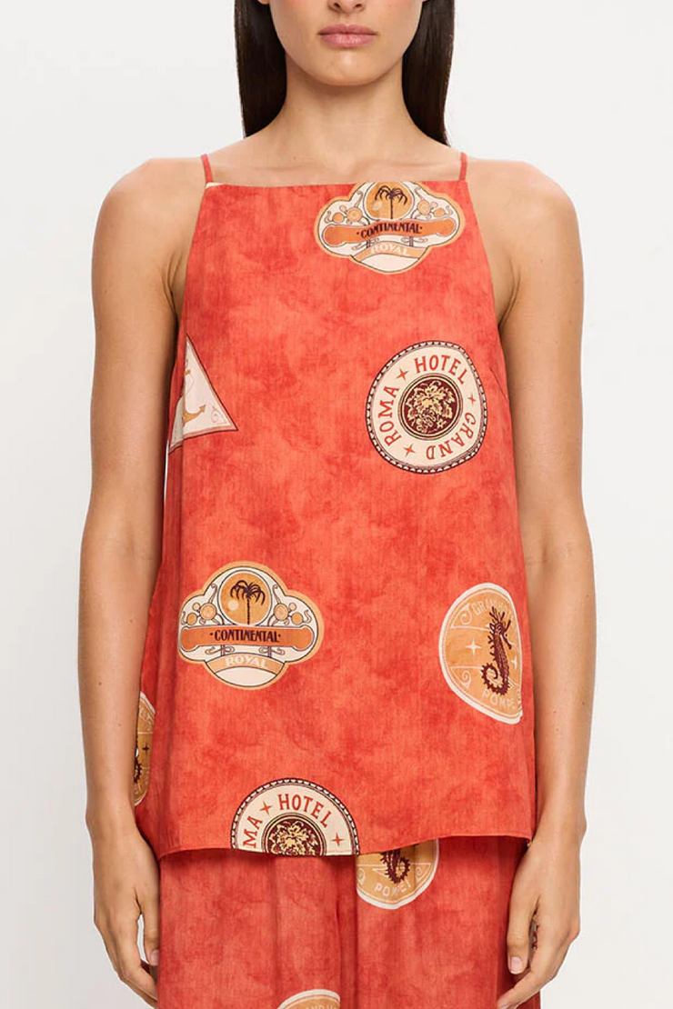 Red sleeveless top with vintage-style labels worn by a model on a white background
