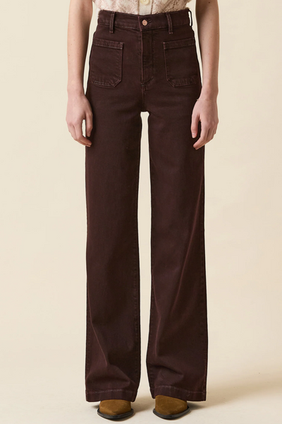 Brown wide-leg jeans worn by a person on a beige background