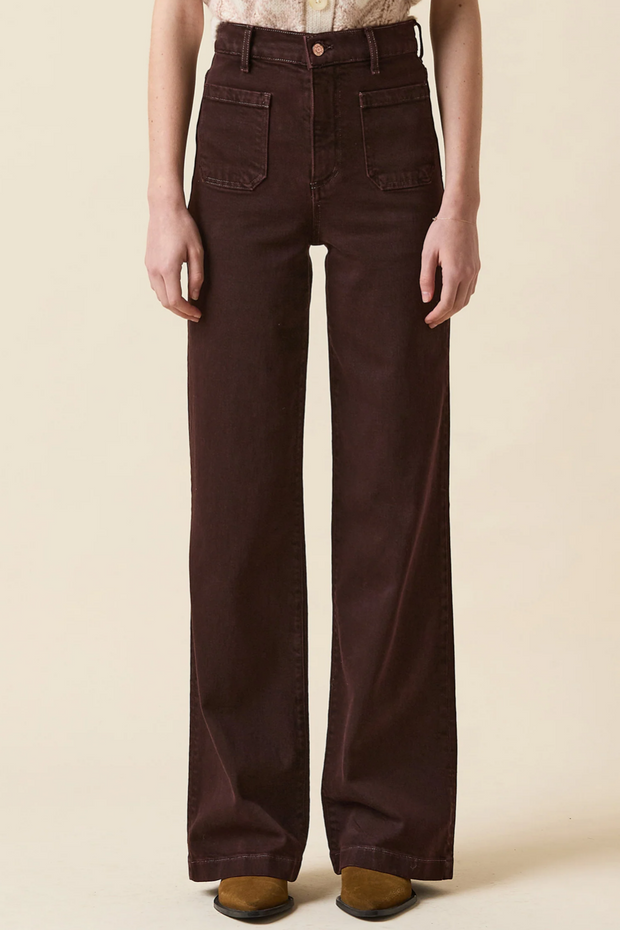 Brown wide-leg jeans worn by a person on a beige background