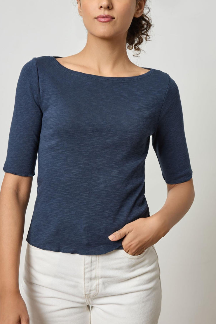 Image of model wearing the lilla p elbow sleeve boatneck front view with one hand in pocket