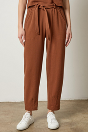 Person wearing praline waffle pants with a tie waist and white sneakers on a plain background