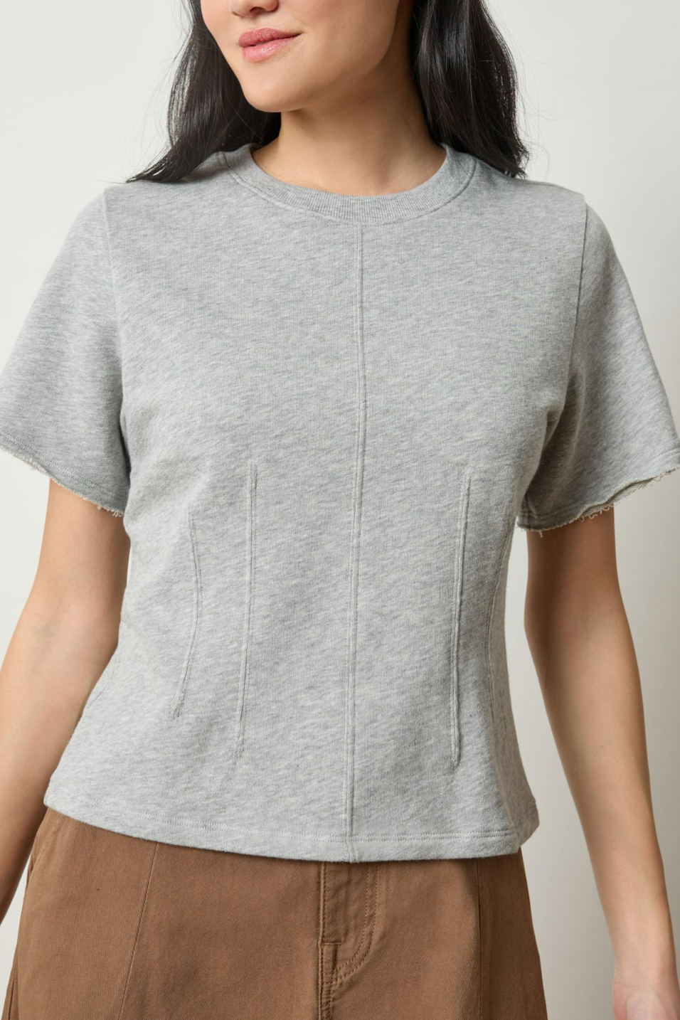 Person wearing a gray short-sleeve top with a plain background