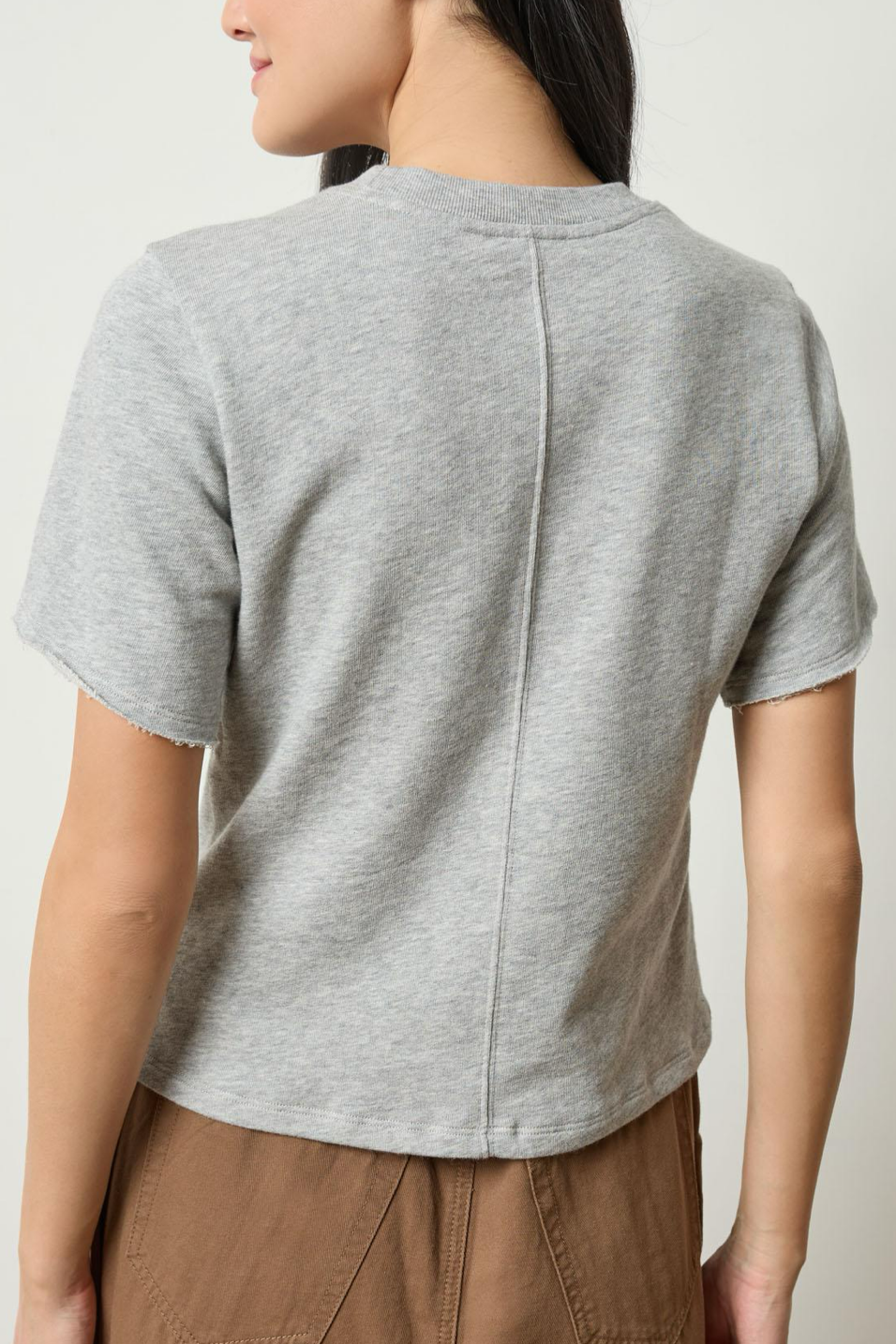 Person wearing a gray t-shirt with a plain background