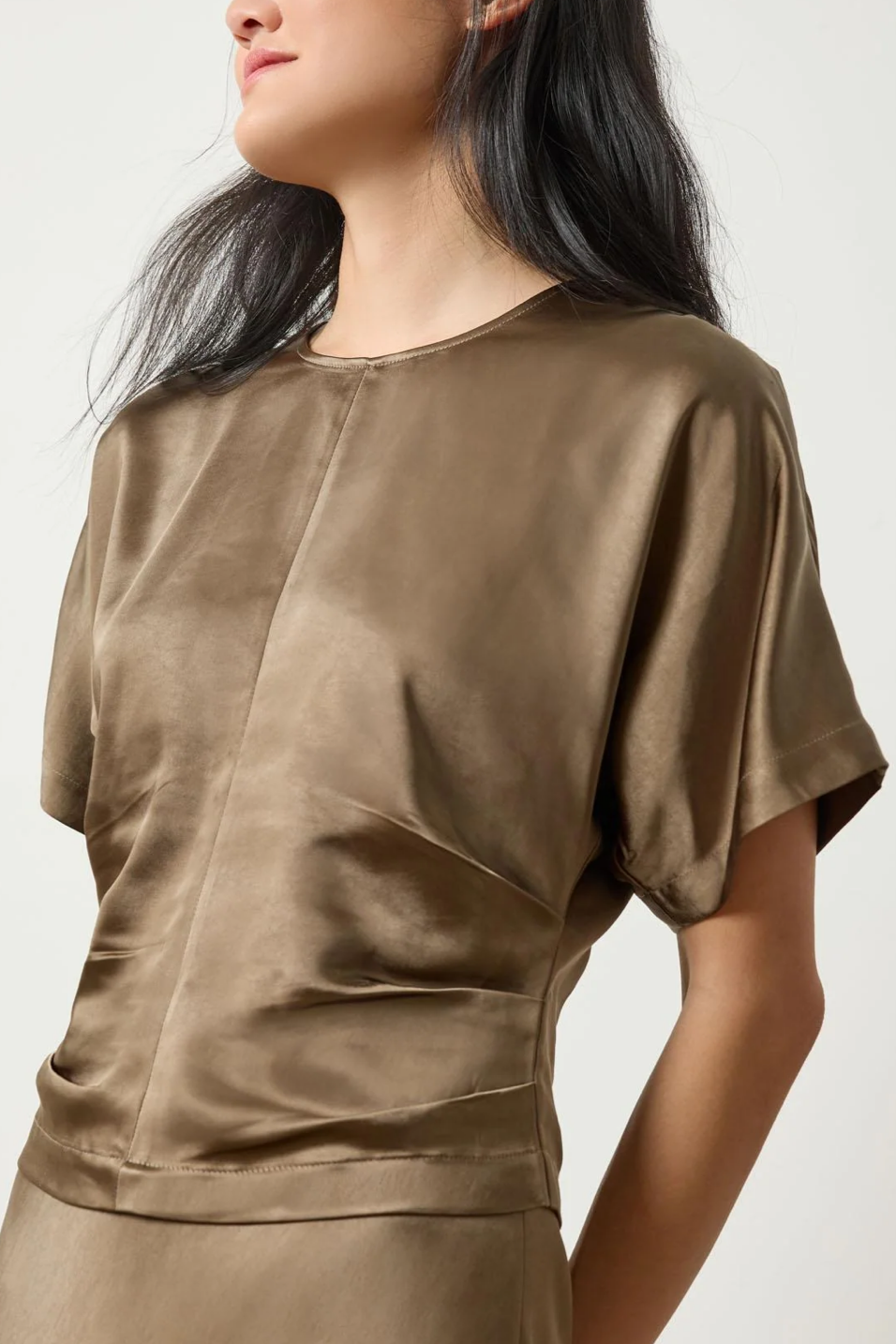 Woman wearing a parsley satin top on a plain background