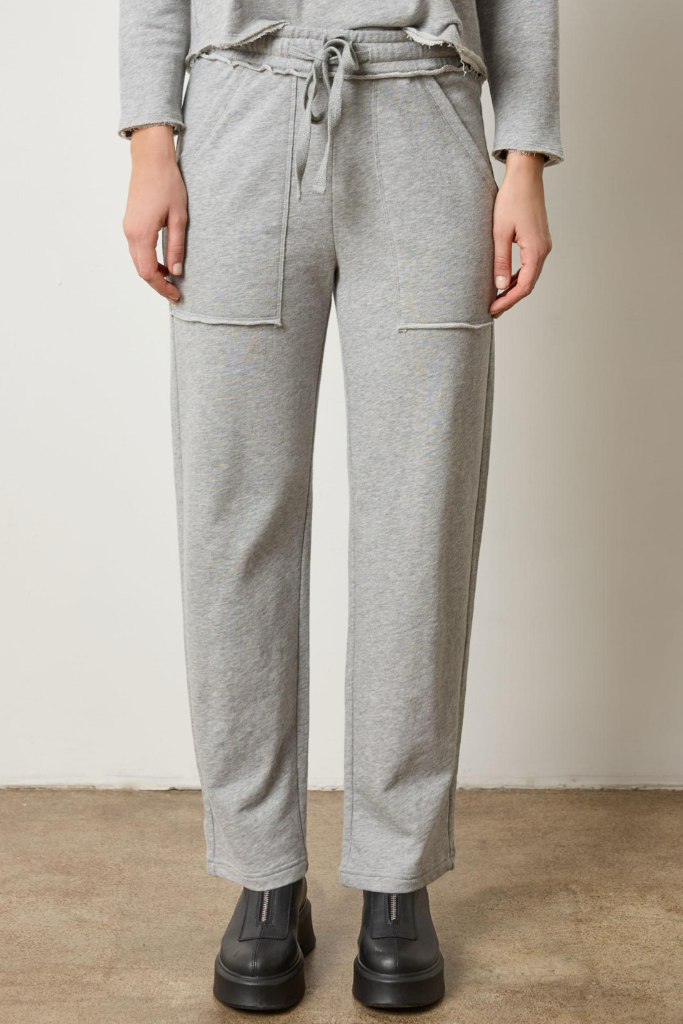 Person wearing gray sweatpants with a plain background