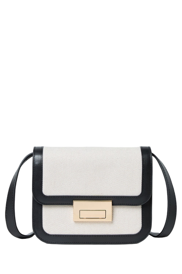 Black and white crossbody bag with a gold clasp on a light gray background