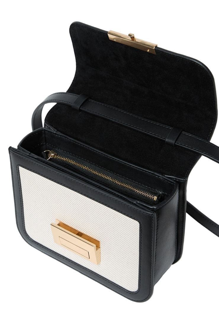 Black and white handbag with gold accents on a light gray background