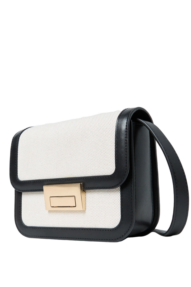 Black and white handbag with a gold clasp on a light gray background