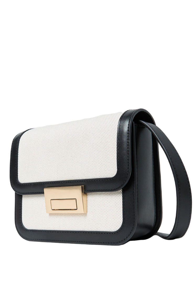 Black and white handbag with a gold clasp on a light gray background