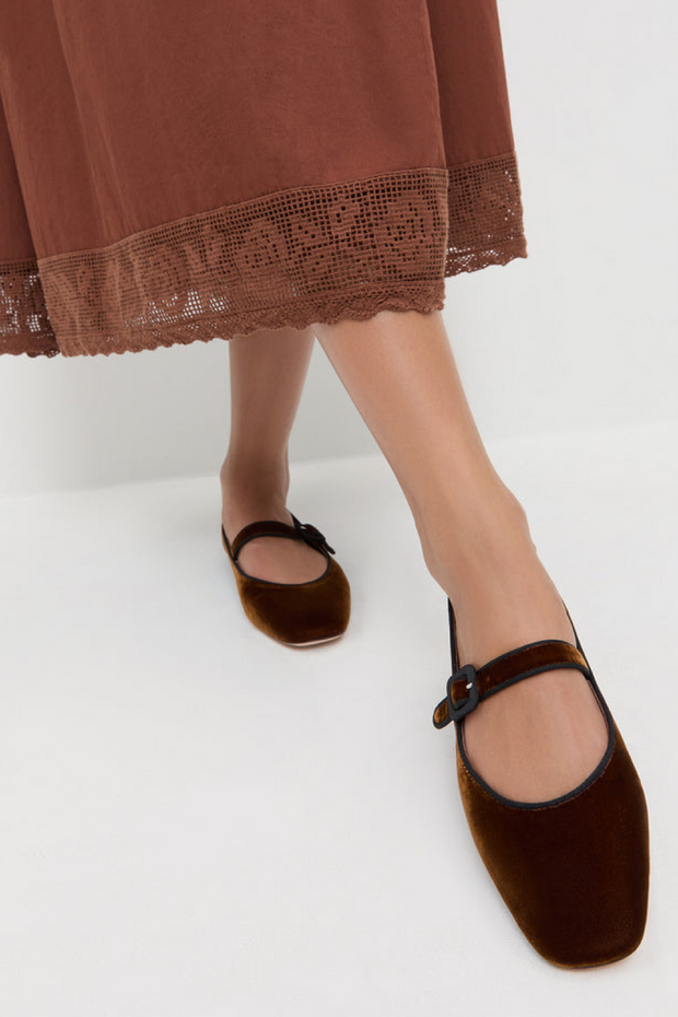 Brown velvet shoes worn with a brown skirt on a white background