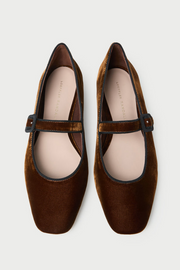 Pair of brown velvet shoes with a strap on a white background