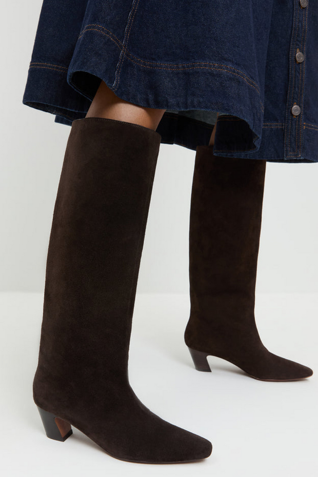 Brown suede knee-high boots worn with a denim skirt on a white background