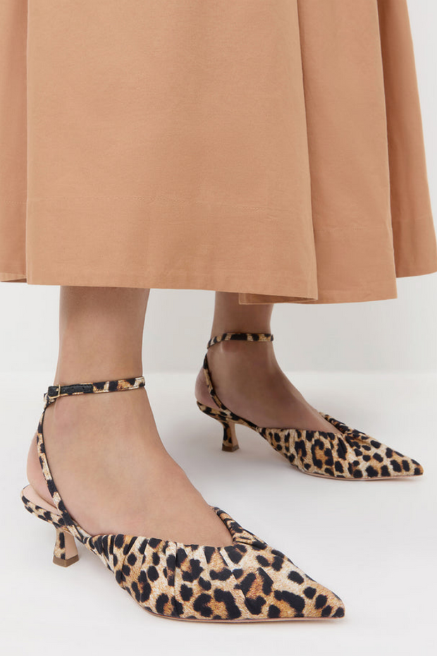 Leopard print kitten heel shoes worn with a tan skirt on a white background
