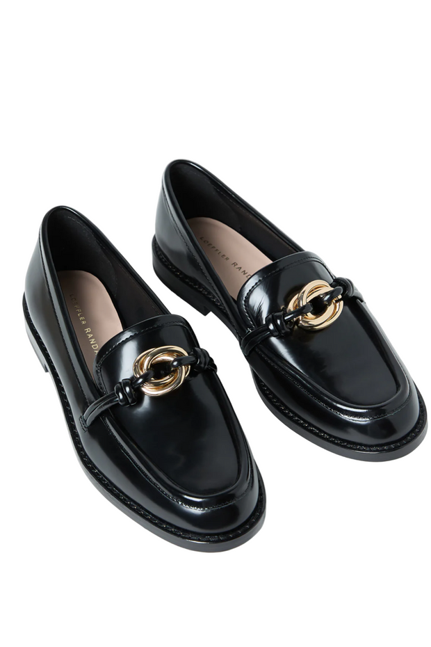Black loafers with gold accents on a white background