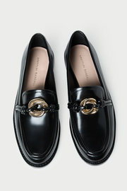 Black loafers with gold accents on a light gray background