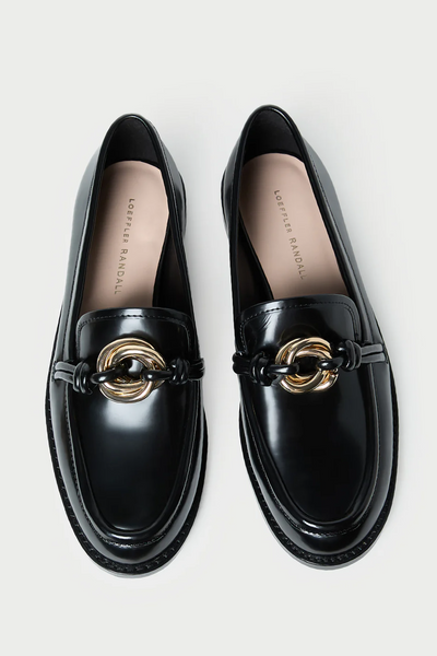 Black loafers with gold accents on a light gray background