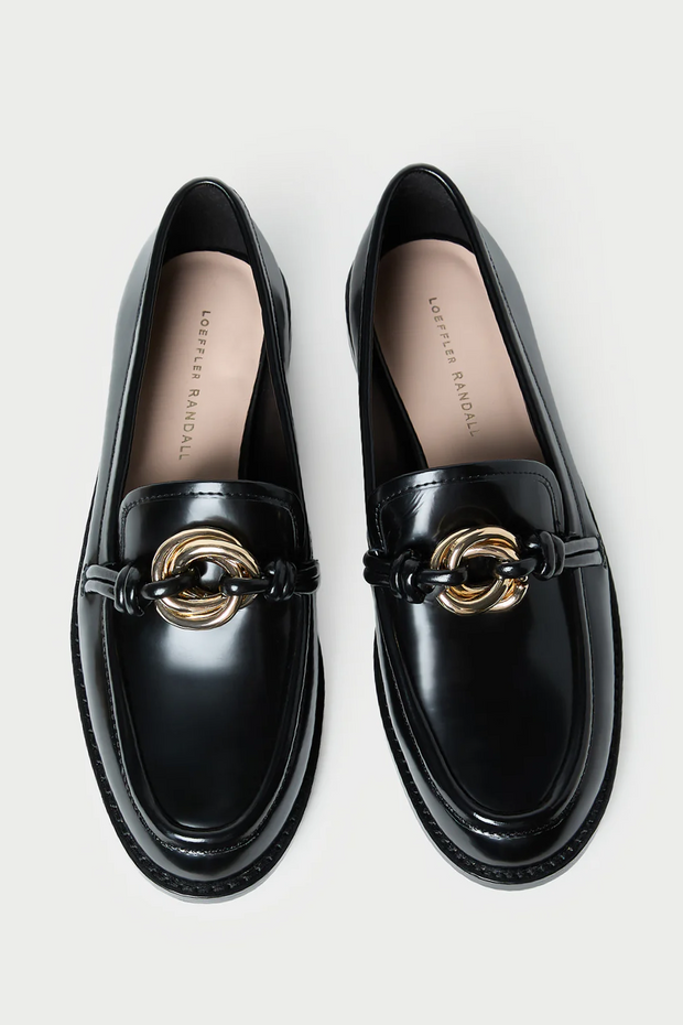 Black loafers with gold accents on a light gray background