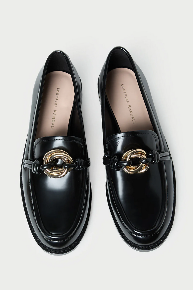 Black loafers with gold accents on a light gray background