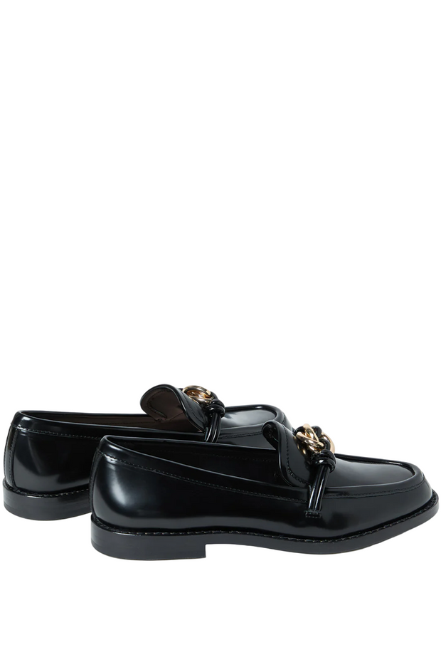 Black loafers with gold accents on a white background