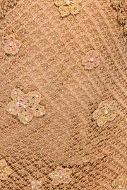 Close-up of beige lace fabric with floral embellishments