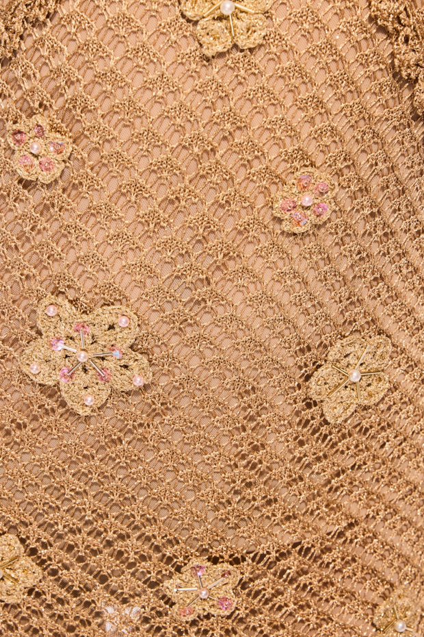 Close-up of beige lace fabric with floral embellishments