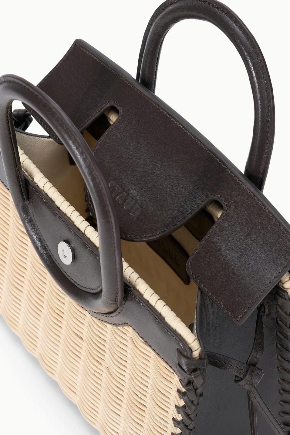 Close-up of a woven handbag with leather handles on a white background