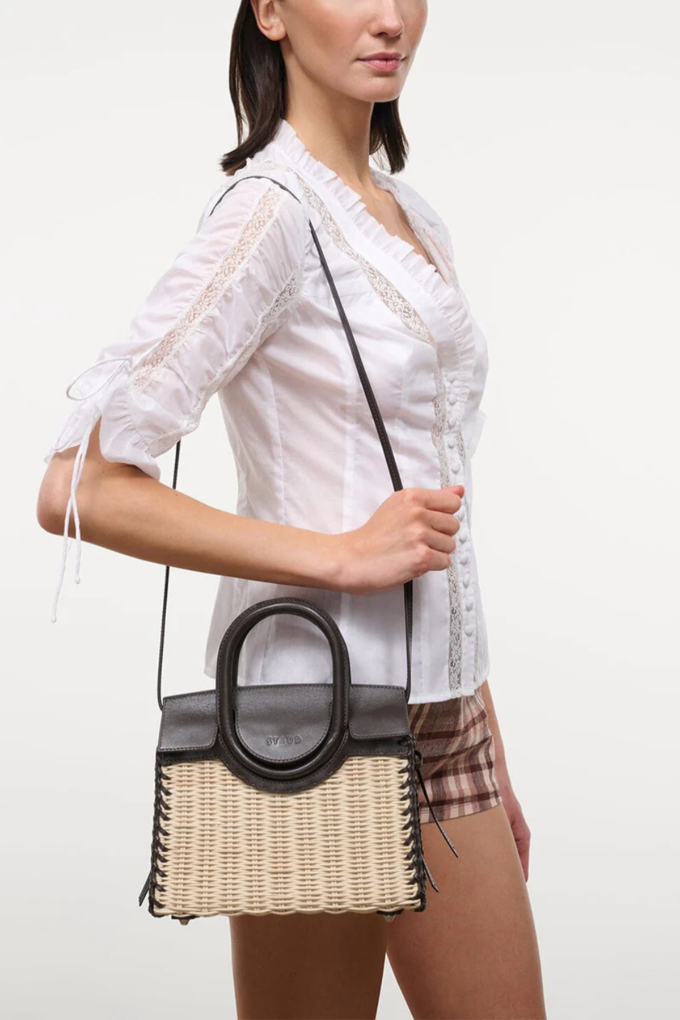 Woman holding a woven handbag with a plain background