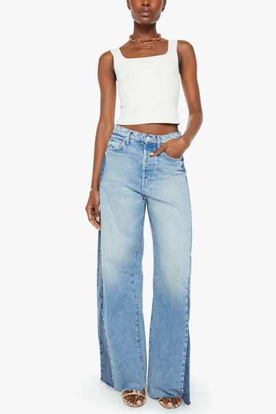 Woman wearing a white sleeveless top and light blue jeans on a white background