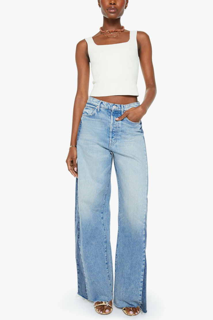 Woman wearing a white sleeveless top and light blue jeans on a white background