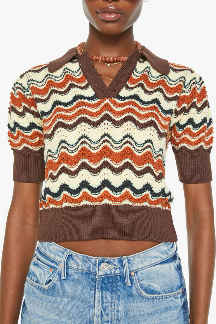 Person wearing a patterned sweater with short sleeves and jeans on a white background