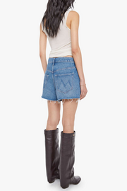 Person wearing a white tank top, blue denim skirt, and black knee-high boots on a white background