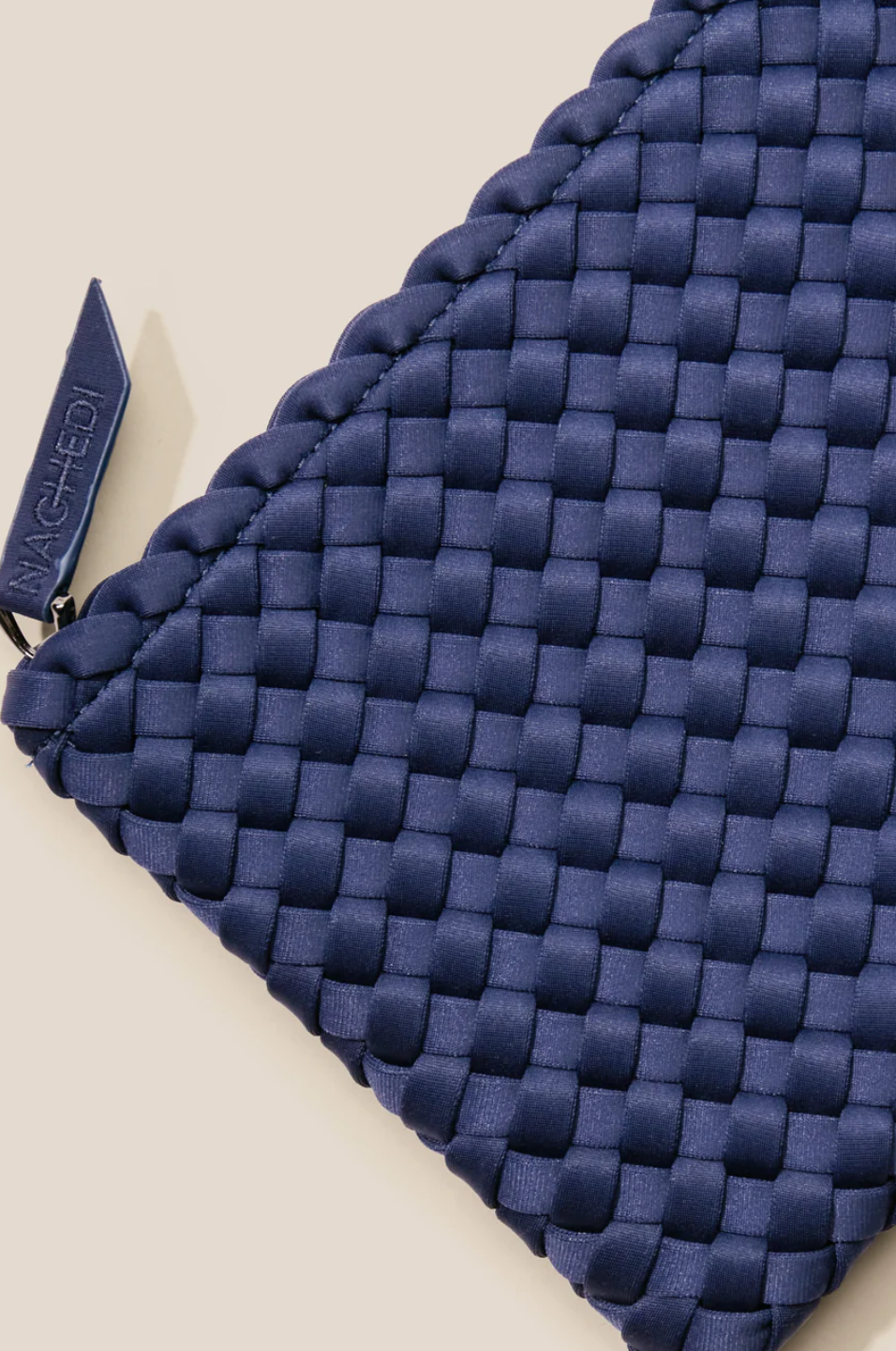 Blue woven pouch with a brand tag on a beige background