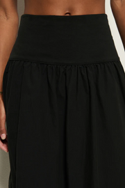Black skirt worn by a person on a neutral background