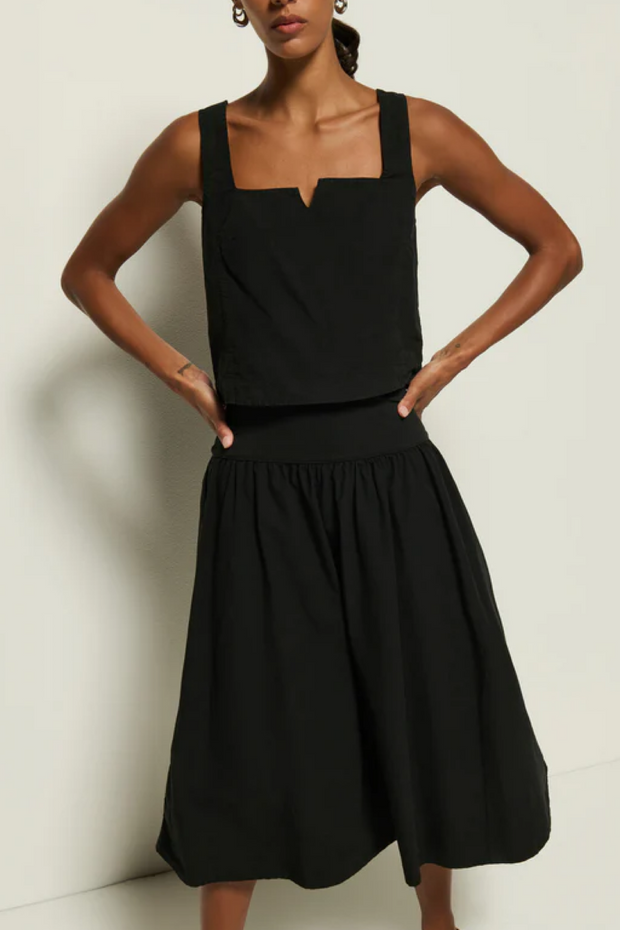 Woman wearing a black sleeveless dress against a plain background