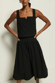 Woman wearing a black tank and skirt against a plain background