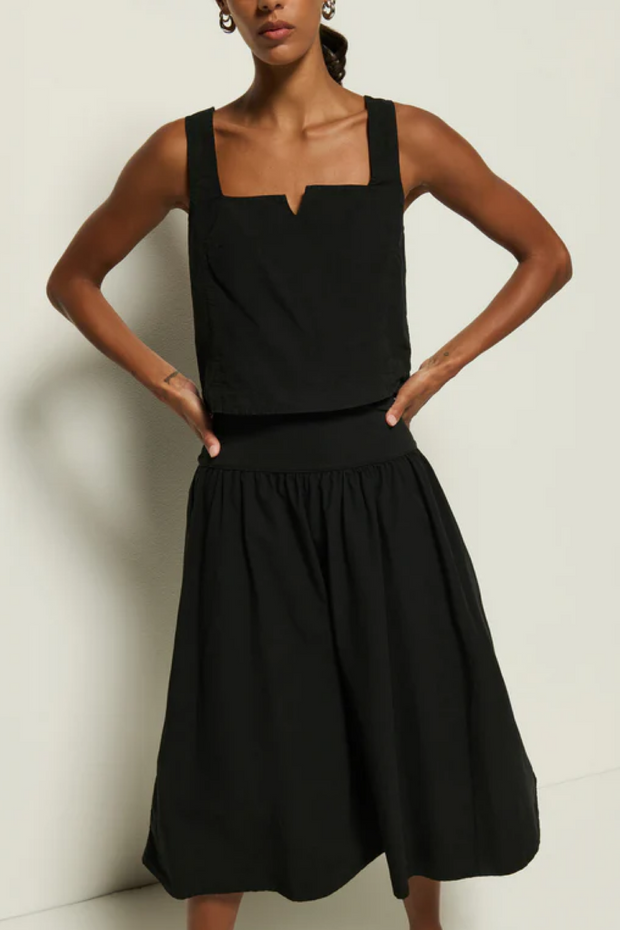 Woman wearing a black tank and skirt against a plain background