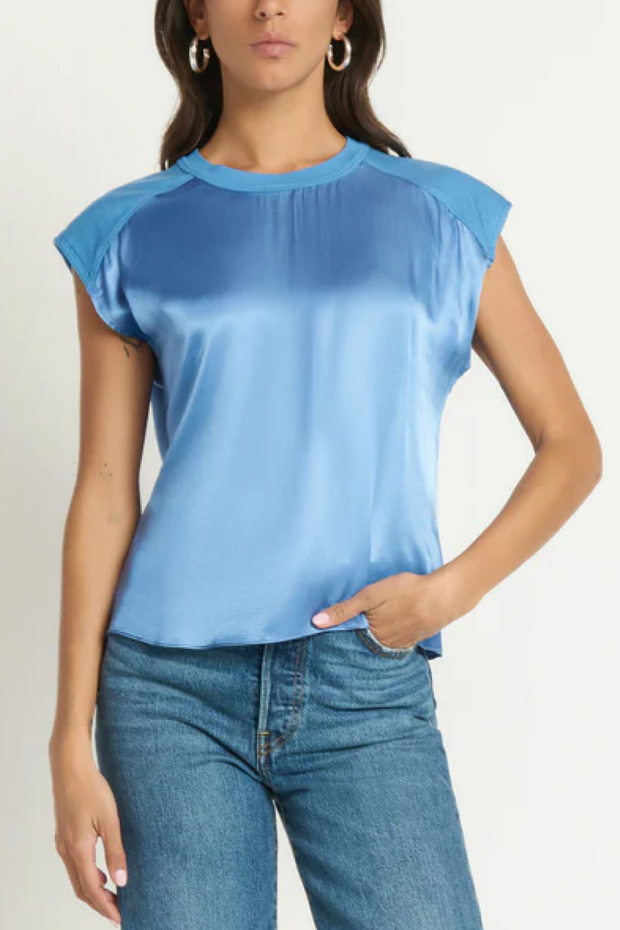 Woman wearing a blue sleeveless top and jeans on a plain background