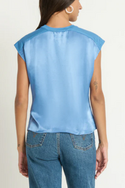 Person wearing a light blue sleeveless top and blue jeans on a plain background