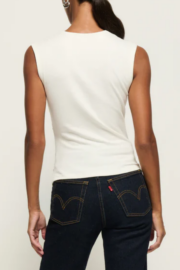 Person wearing a sleeveless top and dark blue jeans with Levi's logo on a plain background