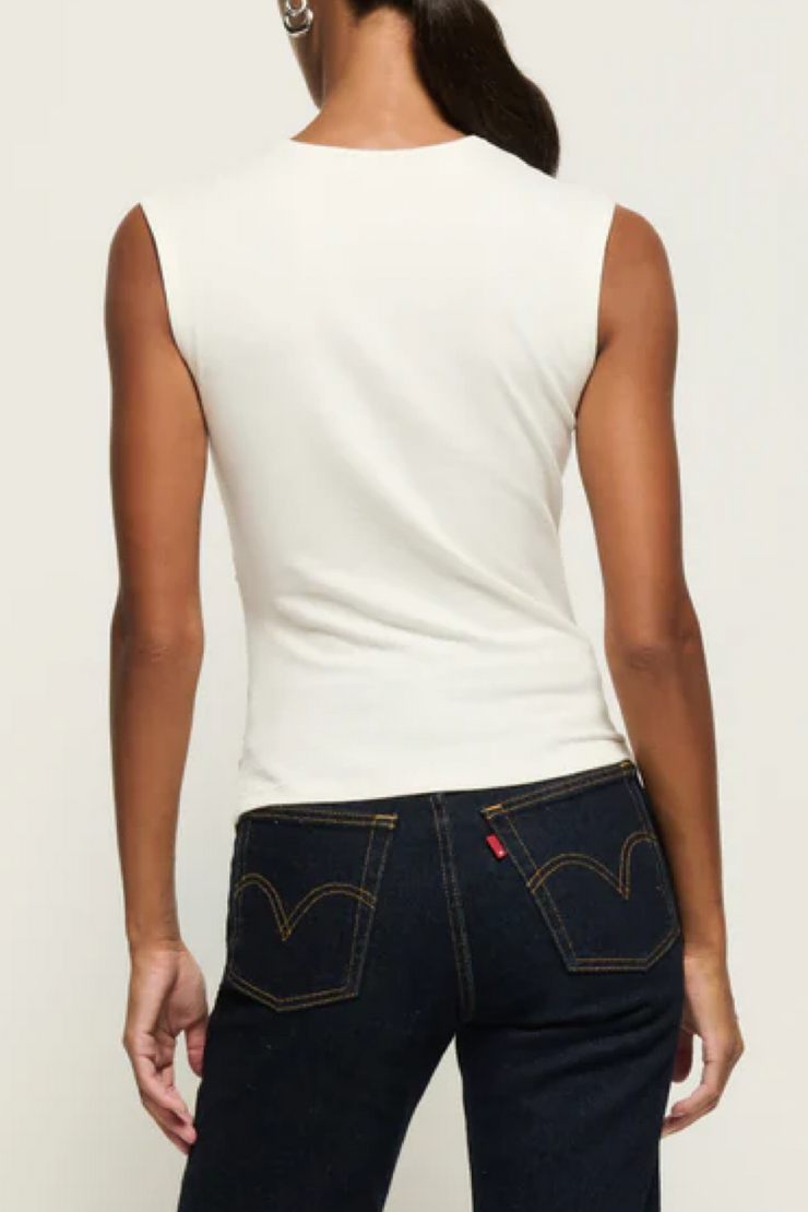 Person wearing a sleeveless top and dark blue jeans with Levi's logo on a plain background